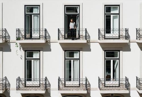 a man stands on a balcony of a building at The Lisboans Apartments in Lisbon