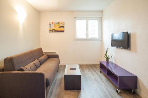 a living room with a couch and a tv at City Résidence Chelles in Chelles