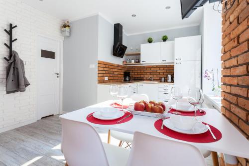 a white kitchen with a white table and chairs at Fahrenheit Centrum Ogarna in Gdańsk
