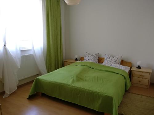 Un dormitorio con una cama verde y una ventana en Jade Apartment, en Hegykő