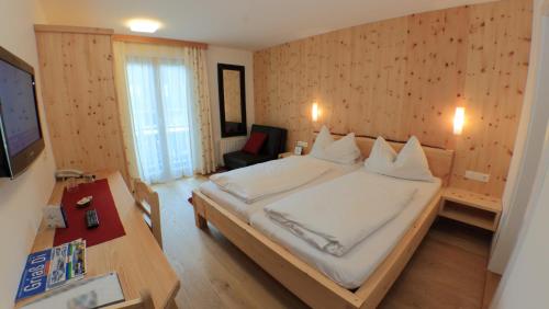 a bedroom with a bed and a desk and a television at Bio-Pension Bliem in Altenmarkt im Pongau