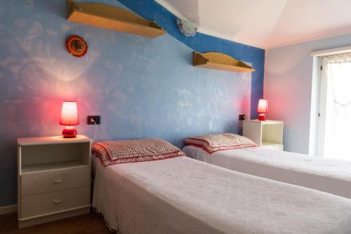 リーヴァ・デル・ガルダにあるResidenza Aironeの青い壁とランプが備わる客室のベッド2台