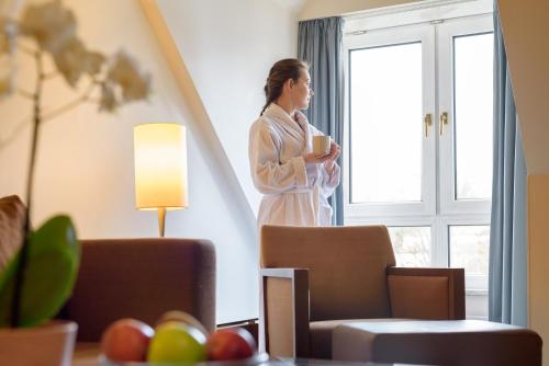 a woman standing in a room looking out the window at Mercure Hotel München Airport Freising in Freising