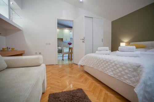 a white bedroom with a bed and a couch at Villa Makarana Apartments in Makarska
