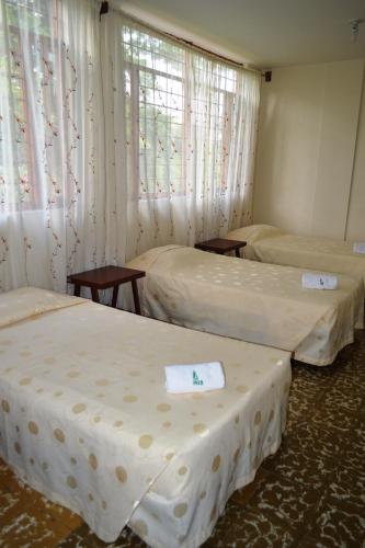 a room with two beds and two tables and a window at Imca Hotel in Buga