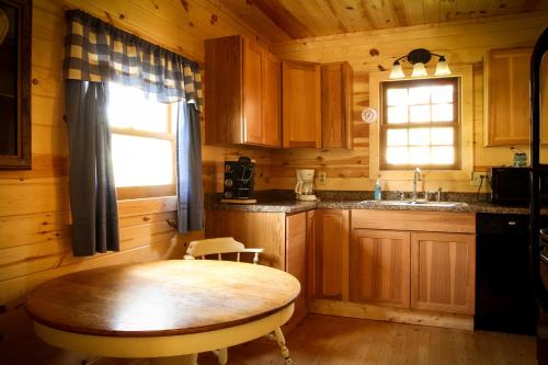 eine Küche mit einem Tisch, einem Waschbecken und einem Fenster in der Unterkunft Cole Cabins in Deadwood