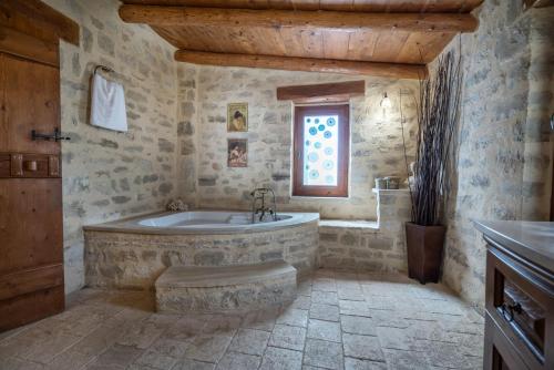 a stone bathroom with a tub and a window at Villa Kalliopi in Prinés