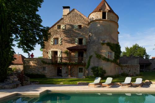 a castle with a swimming pool in front of a house at Mas de Garrigue in Calvignac