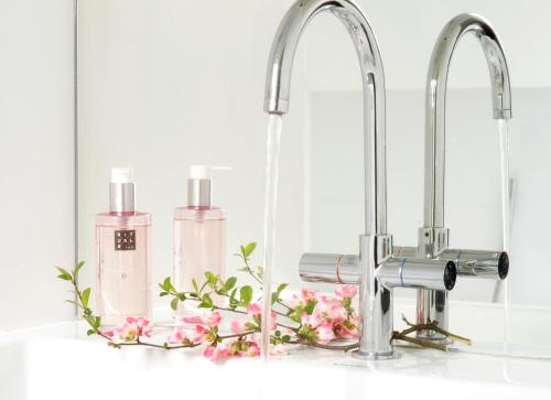 a bathroom sink with two faucets and pink cosmetics at B&B Buitenplaats Natuurlijk Goed in Oosterwolde