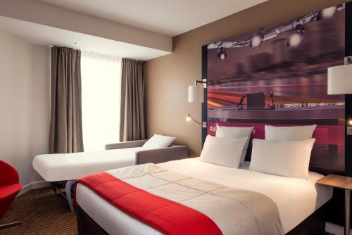 a hotel room with two beds and a red chair at Mercure Paris Boulogne in Boulogne-Billancourt