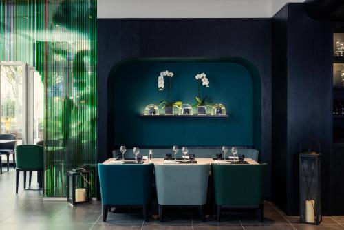 a dining room with two tables and green chairs at Mercure Paris Boulogne in Boulogne-Billancourt
