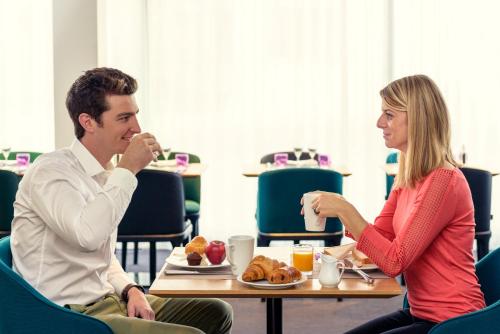 a man and woman sitting at a table eating food at Mercure Paris Boulogne in Boulogne-Billancourt