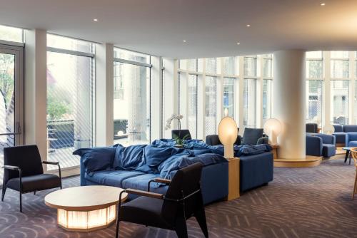 a living room with a blue couch and chairs at Mercure Paris Boulogne in Boulogne-Billancourt