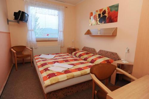 a bedroom with a bed and a table and a window at Borová Sihoť ATC and penzion in Liptovský Hrádok