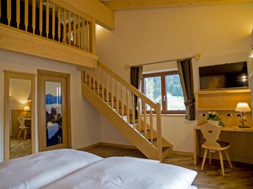 a bedroom with a staircase and a bed and a desk at Hotel El Paster in Pozza di Fassa