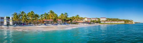 a view of a beach with palm trees and buildings at Pineapple Beach Club - All Inclusive - Adults Only in Willikies