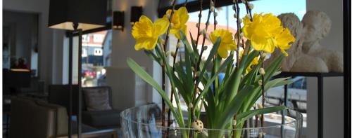 a glass vase filled with yellow flowers on a table at Grand Hotel Belle Vue in De Haan