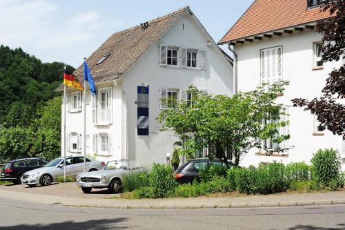 Una casa blanca con autos estacionados frente a ella. en Hotel Restaurant Sengscheider Hof, en Sankt Ingbert