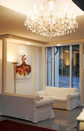 a living room with a white couch and a chandelier at Hotel Restaurant Sengscheider Hof in Sankt Ingbert