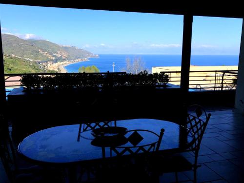 una mesa y sillas en un balcón con vistas al océano en Taormina Lux & Elite Apartments - Taormina Holidays, en Taormina