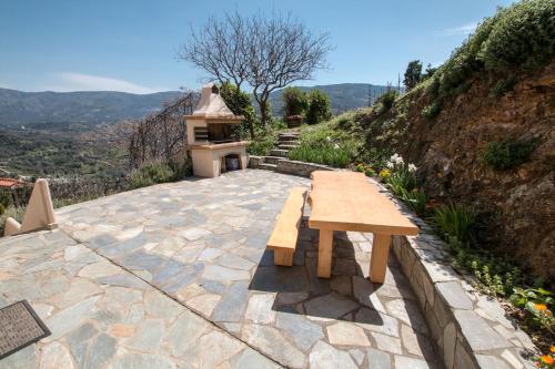 a wooden bench sitting on a stone patio with a hill at Aori Hillside Villa in Kántanos