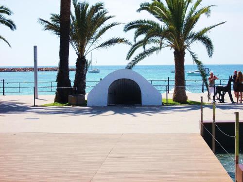 a building on the beach with palm trees and the ocean at Hostal Rey in Santa Eularia des Riu