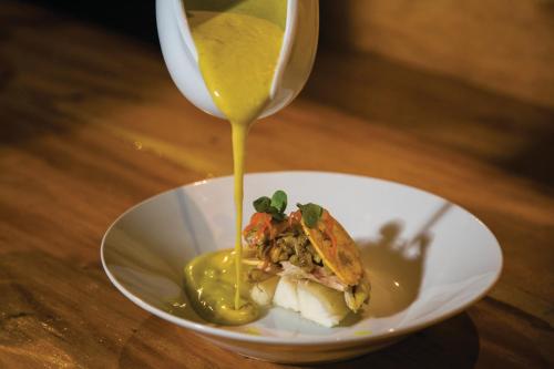 a white bowl with a sandwich with mustard and a spoon at Ämak Iquitos Ecolodge - All Inclusive in Santa Clara