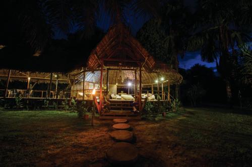 a tree house with a bed in the yard at night at Ämak Iquitos Ecolodge - All Inclusive in Santa Clara