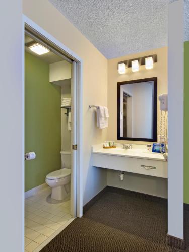a bathroom with a toilet and a sink and a mirror at Baymont by Wyndham Fort Collins in Fort Collins