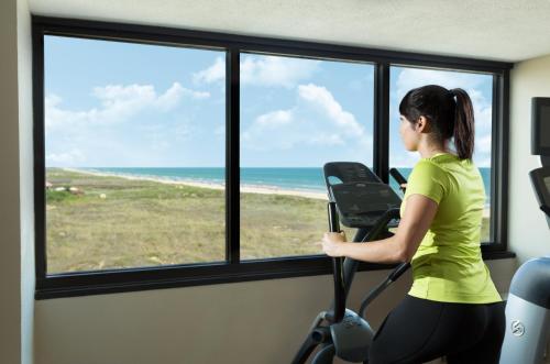 a woman riding a treadmill in a room with a view of the ocean at Margaritaville Beach Resort South Padre Island in South Padre Island