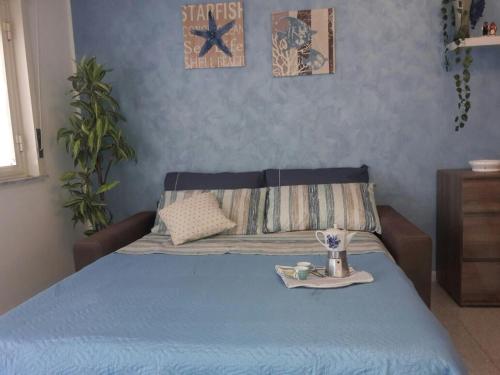 ジャルディーニ・ナクソスにあるcasa vacanza porta naxos giardini sicilia taorminaのベッド(青いベッドカバー付)、トレイ(食べ物プレート付)
