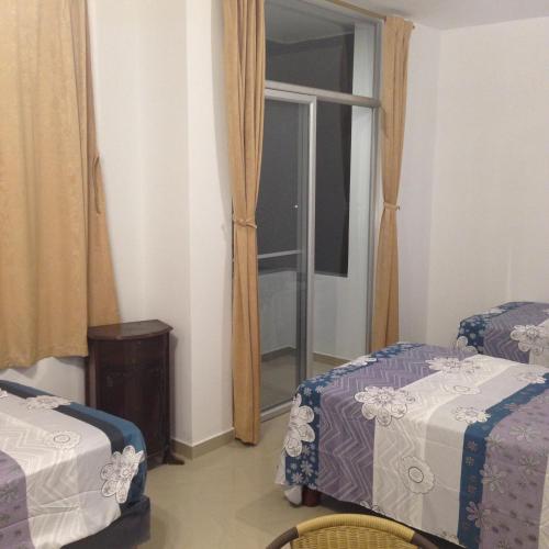 a hotel room with two beds and a window at Hotel Almond Beach in Tonsupa