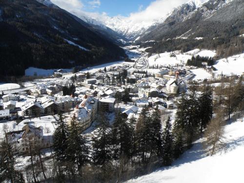 uma aldeia coberta de neve com montanhas ao fundo em Gasthof Moarwirt em Colle Isarco