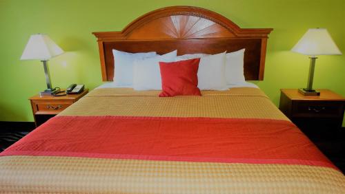 a bedroom with a large bed with a red pillow at Oak Tree Inn & Suites in Claxton