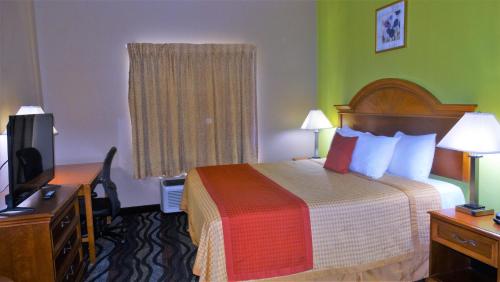 a hotel room with a bed and a desk and a television at Oak Tree Inn & Suites in Claxton