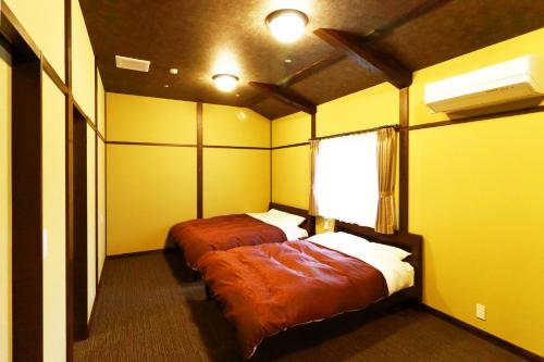 two beds in a room with yellow walls at Ryokan Karasawa in Kanazawa