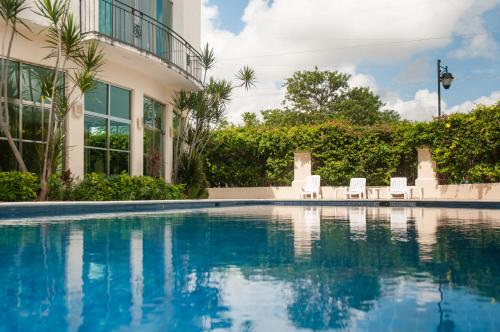 a swimming pool with chairs and a building at Boutique House Cancun by Elevate Rooms in Cancún