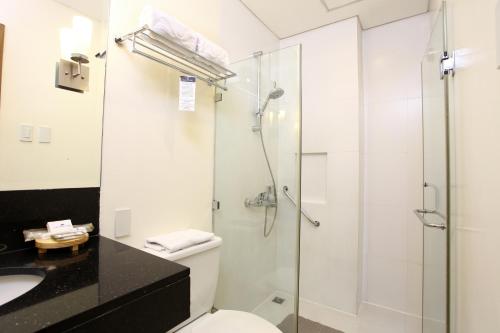 a bathroom with a shower and a toilet and a sink at City Garden Suites Manila in Manila