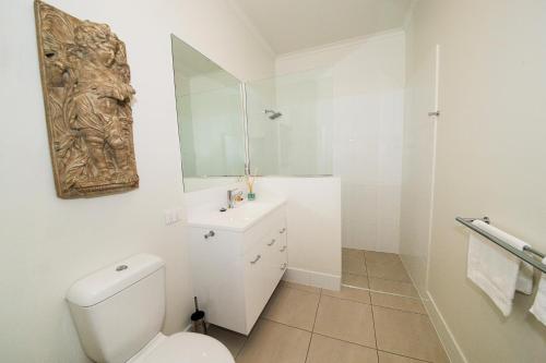 a white bathroom with a toilet and a sink at Bank House Tamborine Mountain in Mount Tamborine