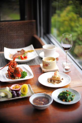 a wooden table with plates of food and a glass of wine at Mudanwan Villa in Mudan