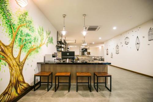 a restaurant with a bar with three stools and a tree mural at Urban Inn, Jitra in Jitra