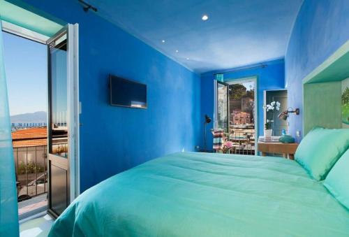 1 dormitorio azul con 1 cama grande y balcón en Estate4home - La Grotta Azzurra, en Sorrento