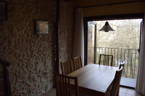 een eettafel met stoelen en een groot raam bij Ca La Tambona in Sant Felíu de Pallarols