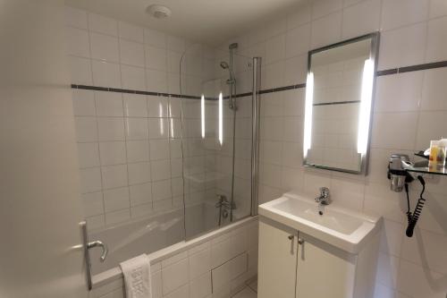 a bathroom with a tub and a sink and a shower at Rex Résidence in Tarbes