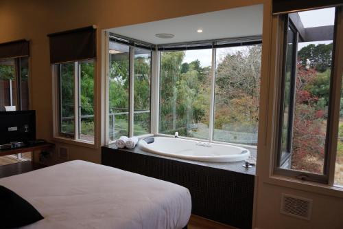 a bedroom with a bath tub and a large window at Indulge at Daylesford in Daylesford