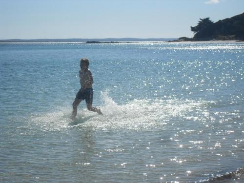 a man on a surfboard in the water at White Sands in Rangiputa