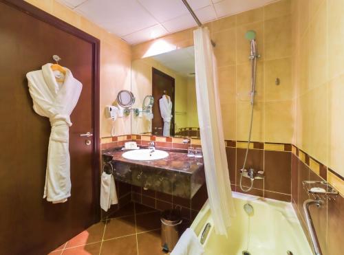 a bathroom with a sink and a tub and a mirror at Executive Suites Abu Dhabi in Abu Dhabi