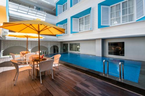 een zwembad met een tafel en stoelen en een parasol bij Yan's House Hotel in Kuta