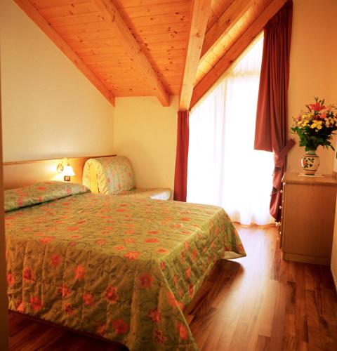 a bedroom with a bed with a green comforter and a window at Residence Kristall- Fiemme Holidays in Predazzo