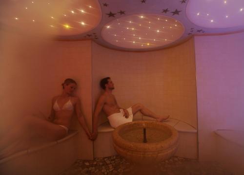 2 personnes assises dans une baignoire dans une salle de bains dans l'établissement Residence Kristall- Fiemme Holidays, à Predazzo